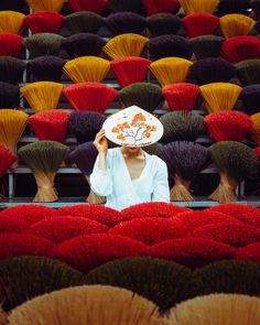 a woman with a hat on her head standing in front of rows of fake flowers