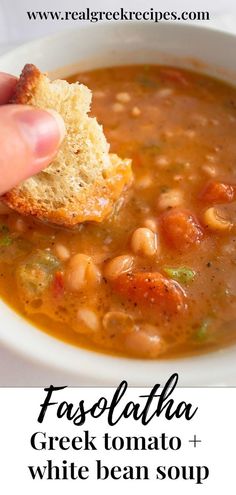 a hand holding a piece of bread over a bowl of faslatha greek tomato and white bean soup