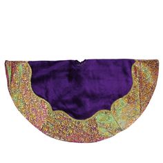 a purple and green purse with gold trimmings on the bottom, sitting on a white surface