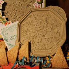 some cookies and ribbons are laying on the table next to an ornate cookie mold that is shaped like a snowflake