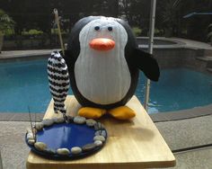 a penguin statue sitting on top of a table next to a pool