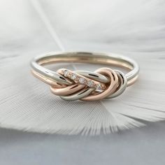 two tone gold and silver ring with three diamonds on the top, sitting on a feather