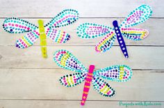 three colorful dragon shaped paper clips sitting on top of a white wooden table next to a pencil