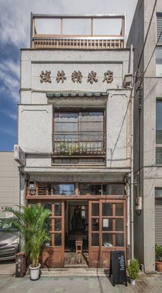 an old building with chinese writing on the front door and windows, along with potted plants