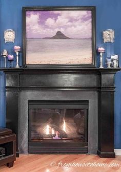 a fire place in a living room with a painting on the wall above it's mantle