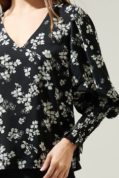 Transition through the seasons in style with the Kennie Floral Smocked Long Sleeve Blouse! This gorgeous black and white floral print shapes this top that has a v-neckline and bouncy long sleeves with elastic smocked cuffs. Easy to wear with any pants to match the floral print and some flats for a comfy yet stylish look. - V-neck- Smocked cuffs- Relaxed fit- Puff sleeves- Color: Black whiteSize + Fit - Model is 5'8" and wearing size XS- Measurements taken from size S - Chest: 18 1/2"- Length: 25 Spring V-neck Smocked Top With Gathered Sleeves, Spring Floral Print V-neck Smocked Top, V-neck Smocked Top For Brunch, Long Sleeve Smocked Top With Floral Print For Brunch, Long Sleeve Floral Smocked Top For Brunch, Floral Print V-neck Smocked Top For Brunch, Chic V-neck Smocked Top With Blouson Sleeves, Fall V-neck Smocked Top With Blouson Sleeves, Chic Smocked Top With V-neck And Blouson Sleeves