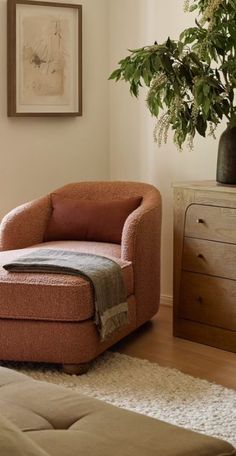 a living room with a chair, ottoman and potted plant