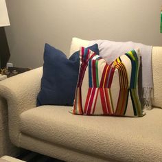 a white couch with colorful pillows on top of it next to a table and lamp