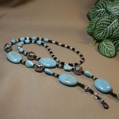 "This eyeglass chain has 4 large turquoise gemstone beads (a bit over 1\" long), smaller teardrop shaped turquoise gemstone beads, decorative silver metal beads in 2 sizes, and black & silver glass seed beads. You will never misplace your glasses again!! Length - 30\" Weight - 2.26 oz (63 Grams) Multi-strand flexible stringing wire Silicone ends" Turquoise Jewelry With Black Beads For Festival, Silver Turquoise Necklace With Round Beads, Silver Turquoise Necklace With Round Beaded Chain, Adjustable Turquoise Jewelry With Black Beads, Adjustable Turquoise Beaded Chain, Turquoise Teardrop Beaded Chain Jewelry, Turquoise Jewelry With Black Beads, Turquoise Teardrop Jewelry With Beaded Chain, Turquoise Teardrop Beaded Jewelry