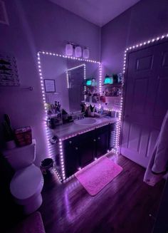 a bathroom with purple lights on the wall and a pink rug in front of it