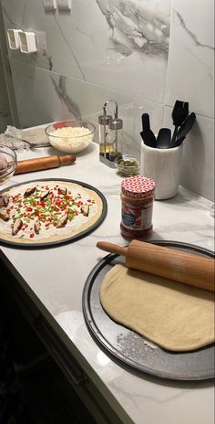 two uncooked pizzas sitting on top of a counter