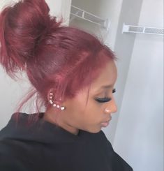 a woman with red hair and black eyeliners wearing a pair of ear rings