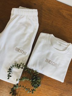 the bride and groom's personalized pajamas are laid out on a wooden table