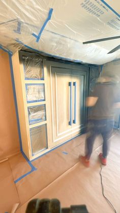 a man is painting the inside of a room with blue tape on the walls and windows