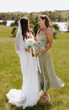 two women in dresses standing next to each other on a field with grass and flowers