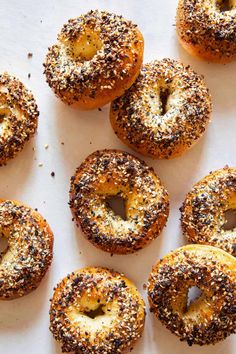 bagels with sesame sprinkled on them sitting on a white surface