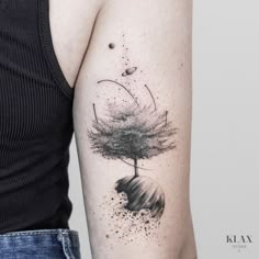 a woman's arm with a tree on top of it and planets in the background