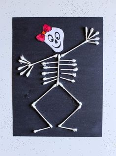 a paper skeleton with a red bow on it's head