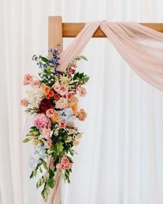 a wooden cross decorated with flowers and greenery for a wedding ceremony or special event