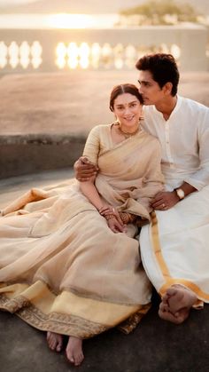 a man sitting next to a woman on top of a cement floor in front of a building