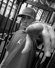 a young man is holding his hand up in front of the camera while wearing a hat