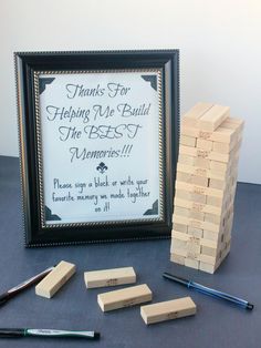 a wooden block tower sitting on top of a table next to a framed sign that says thanks for helping me build the best memories