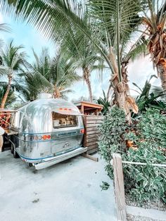 an airstream parked next to some palm trees