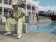 a man sitting next to a swimming pool