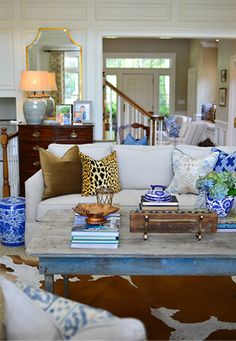 the living room is decorated with blue and white decor, including cow hide rugs