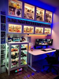 a gaming room with two computers and games on the shelves above it is lit up by blue lights