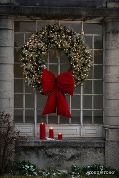 a wreath and two candles on a window sill