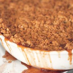 a close up of a pie in a pan with sauce on the bottom and brown crumbs