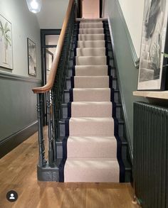 the stairs are lined with pink carpet and black iron railings, along with pictures on the wall