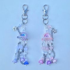 two key chains with charms attached to them on a white surface and one has a star hanging from it