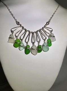 This lovely sea glass necklace made with seafoam, green and white Sea glass dangling on a beautiful formed wire. The sea glass has been churning in the sea, sand and rocks to make a beautiful pieces of sea glass.   My husband and I have been sea glassing avidly for many years. I have been collecting sea glass and other various things from the ocean for most of my life.  We are blessed to live on the beautiful island of Mount Desert, Maine, where 95%of our sea glass is found.  The other 5% is found from other beaches in Maine or Eastern Canada. Product information: material: authentic sea glass  Metal: sterling silver Size: approximately 24 1/2" NL-150 Green Sea Glass Necklace For Jewelry Making, Green Sea Glass Necklaces For Jewelry Making, Green Glass Wire Wrapped Necklace, Green Glass Wire Wrapped Necklaces, Green Wire Wrapped Dangle Necklaces, Green Dangle Necklaces With Wire Wrapped, Handmade Green Sea Glass Necklace, Green Sea Glass Wire Wrapped Jewelry, Eastern Canada