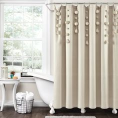 a white bath tub sitting next to a window covered in pom - poms