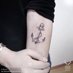 a woman's arm with an anchor tattoo on the left side of her arm