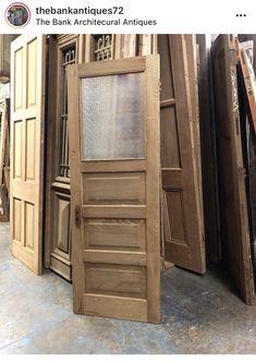 an open wooden door sitting in front of other doors on display at the bank's architectural antiques