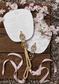 a pair of scissors sitting on top of a table next to pink ribbon and flowers