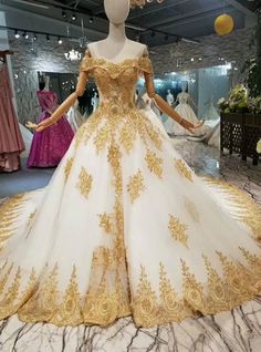 a white and gold wedding gown on display in a room with mannequins