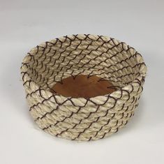 a woven basket is sitting on a white surface with brown lines around the bottom and sides