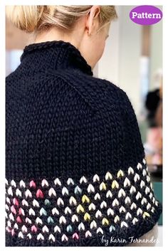 a woman wearing a black knitted sweater with multicolored arrows on the back