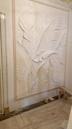 a large white painting on the side of a wall in a room with wood flooring