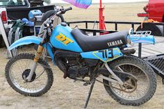 a blue and black dirt bike parked in the sand