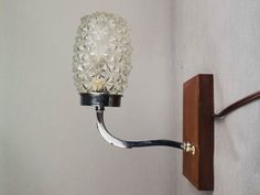 a glass ball light is mounted on the wall next to a wood frame and metal hook