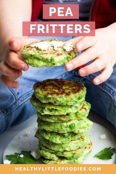 a stack of green pancakes sitting on top of a white plate next to a child's hand