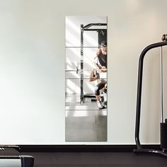 a man is doing squats on a bench in a room with white walls and black flooring