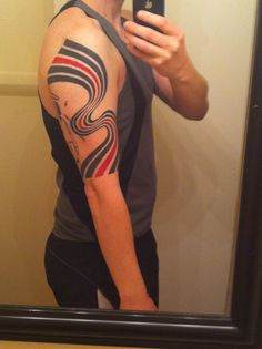 a man taking a selfie in front of a mirror with his arm and shoulder tattoo