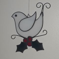 a glass bird ornament hanging from the ceiling with holly decorations on it's side