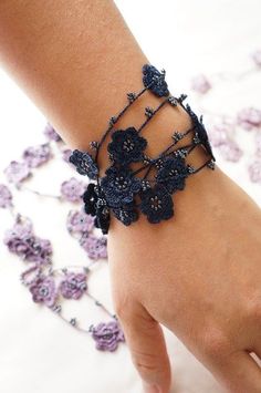 a woman's hand wearing a bracelet with flowers on it